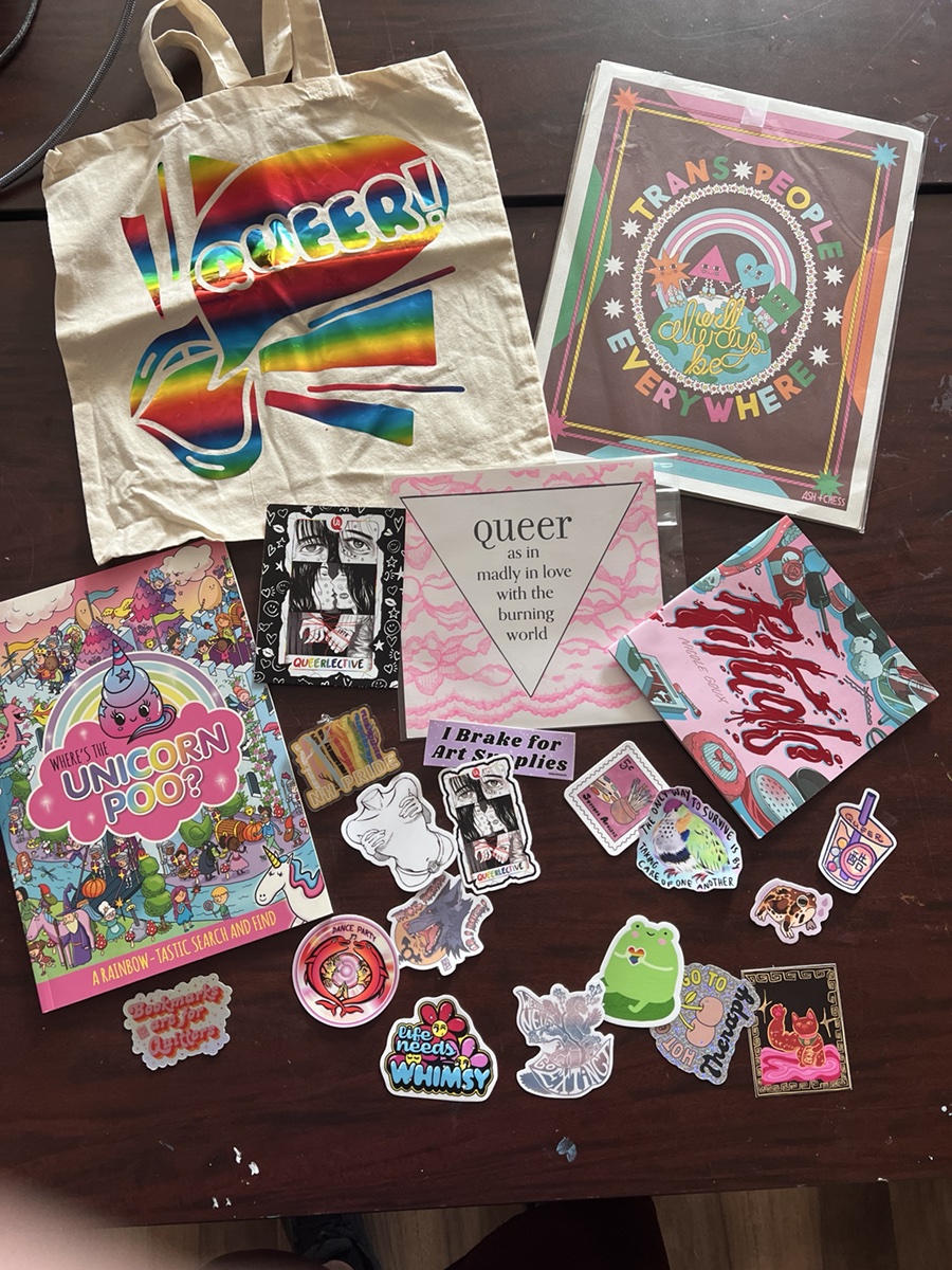 Raffle Basket 3 with a rainbow Queerlective tote, Trans People Everywhere art, book, print, and stickers